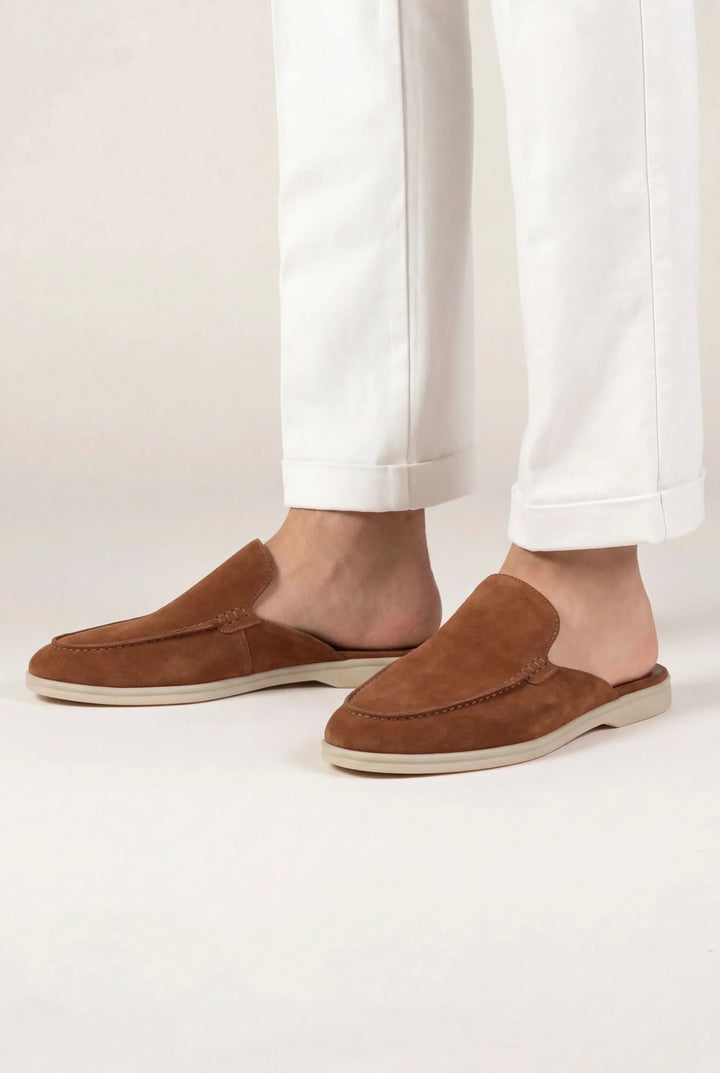 Pair of men's suede mules with open back and flat sole on a plain background