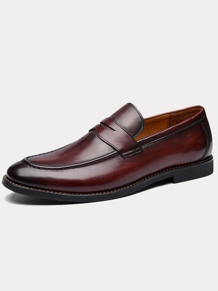 Pair of classic men's leather penny loafers displayed from a side view