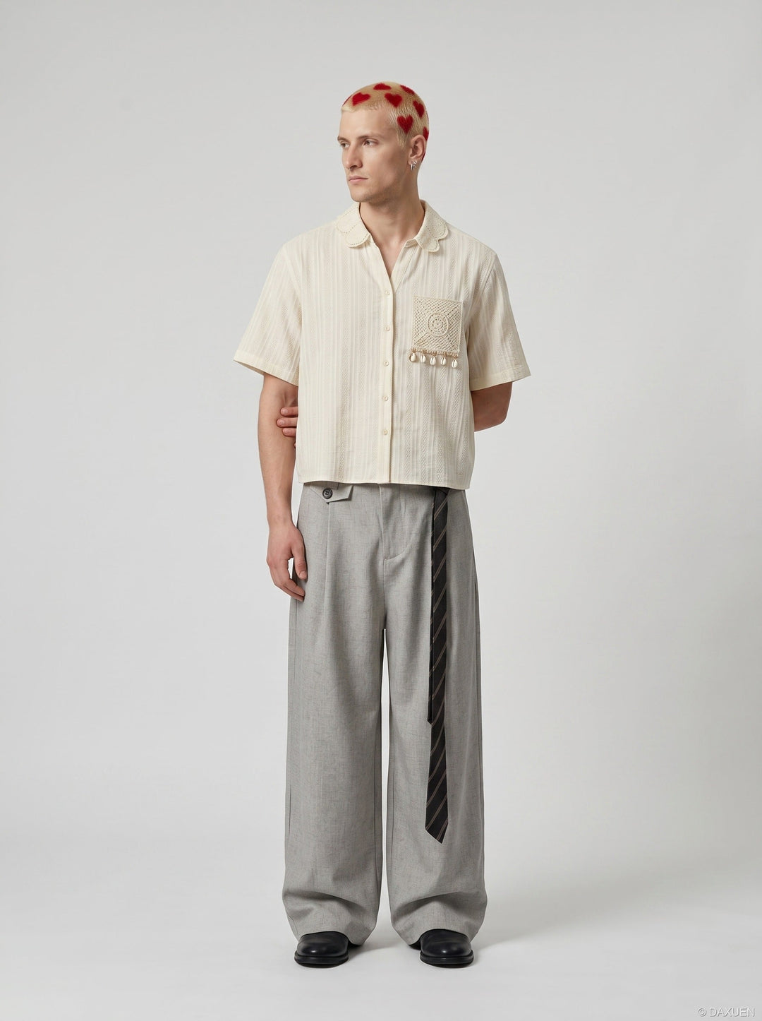 Close-up of embroidered detailing on the cream short sleeve shirt